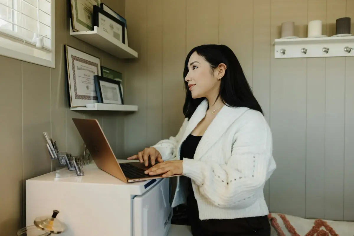 A small business owner working on a laptop at a desk in her office