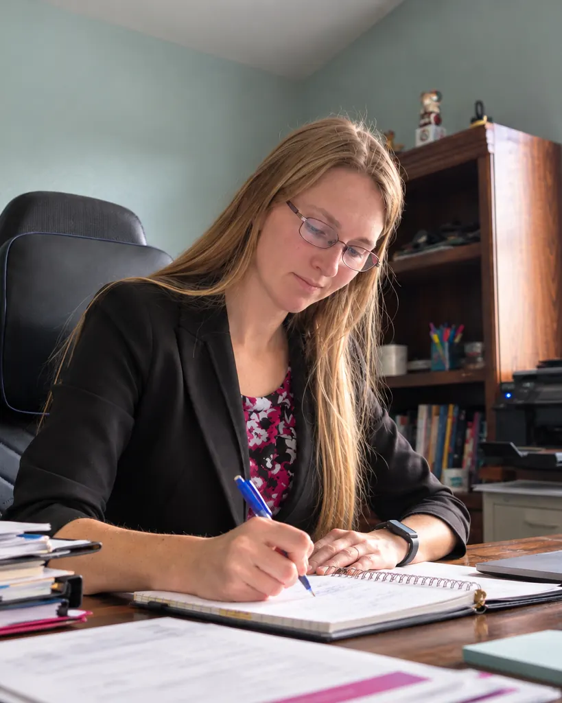 Allisha McCartney writing in a notebook at her desk