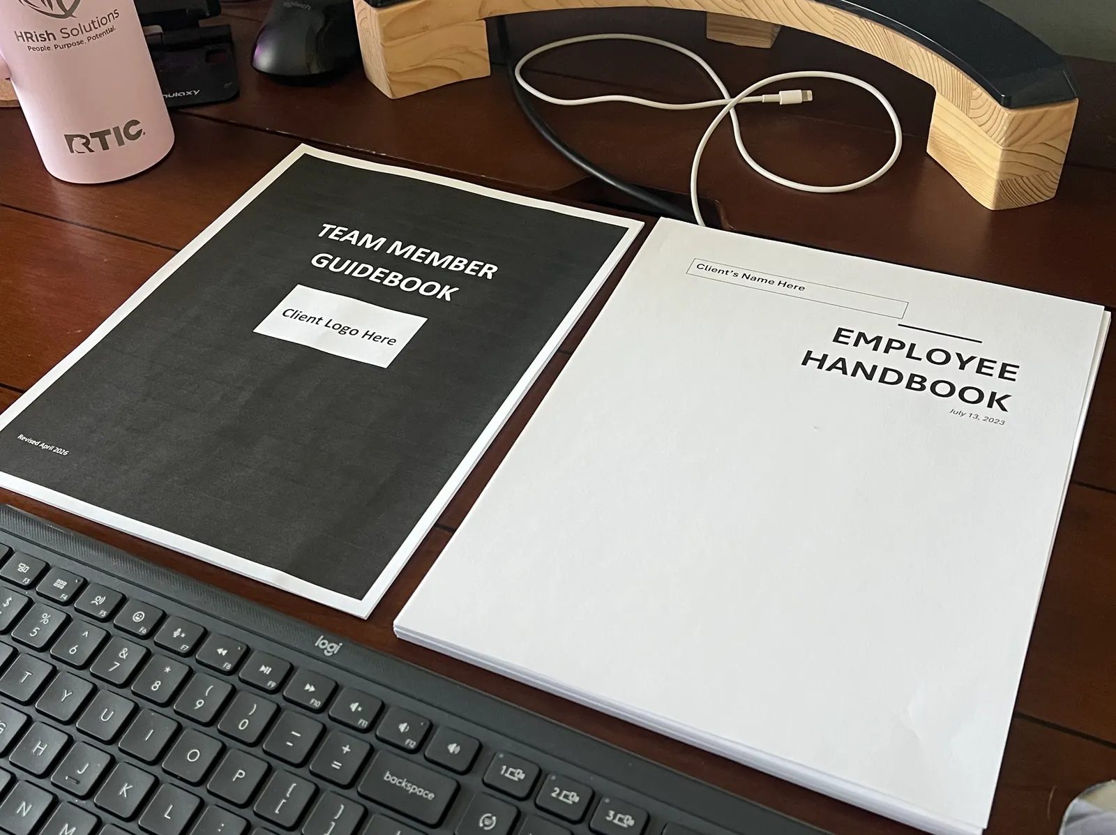 A Team Member Guidebook and an Employee Handbook side by side on a desk